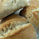 Drei fertig gebackene sogenannte DDR-Brötchen auf bemehlter Arbeitsfläche